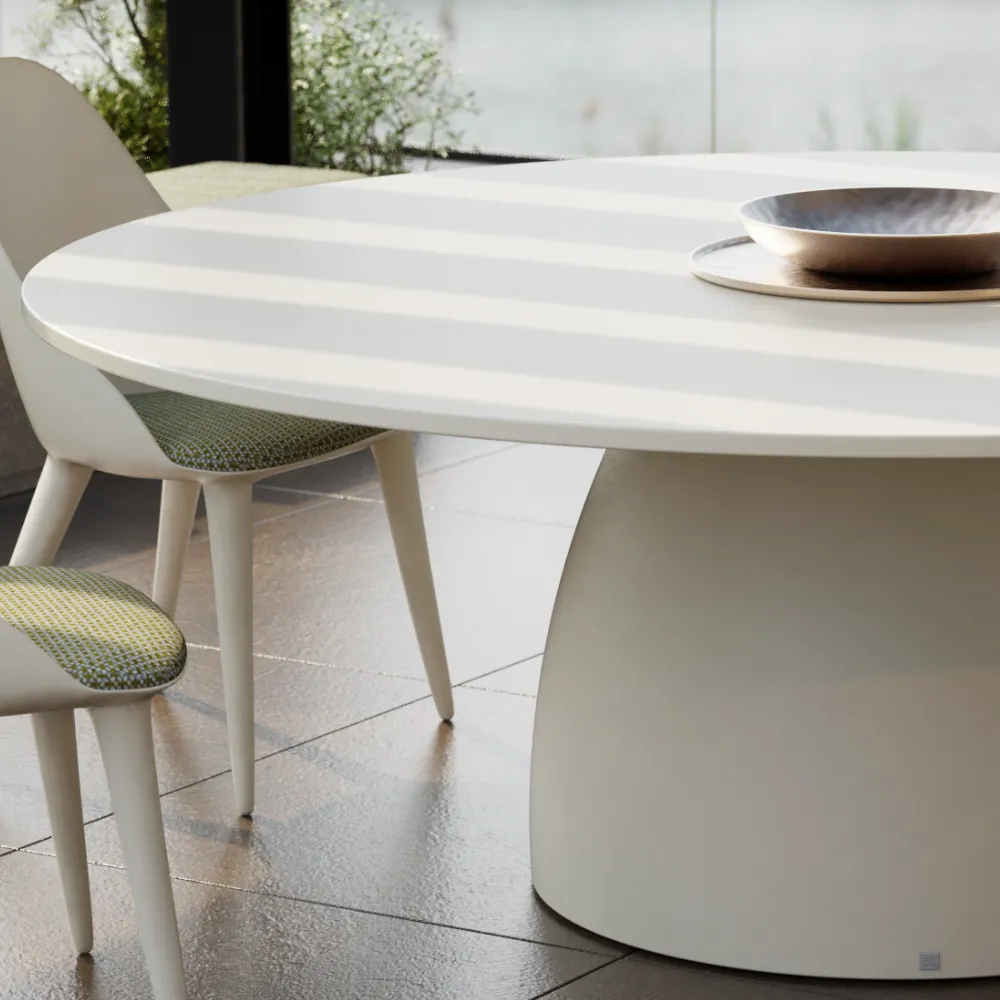 Detail of the white Barrel dining table, showing the thin round top and curved central base on a covered terrace.