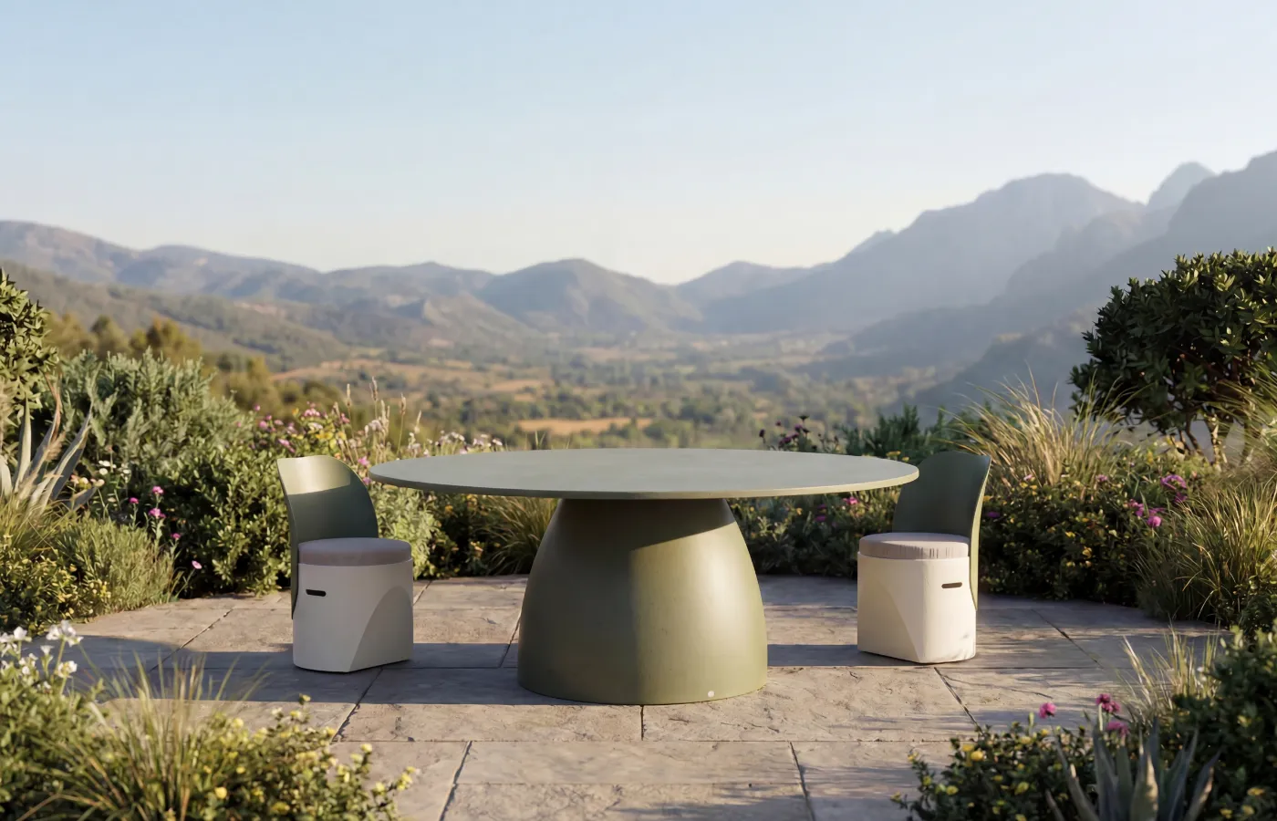 A round green Barrel dining table on a landscaped outdoor terrace, with a wide central base and mountain view in the background.