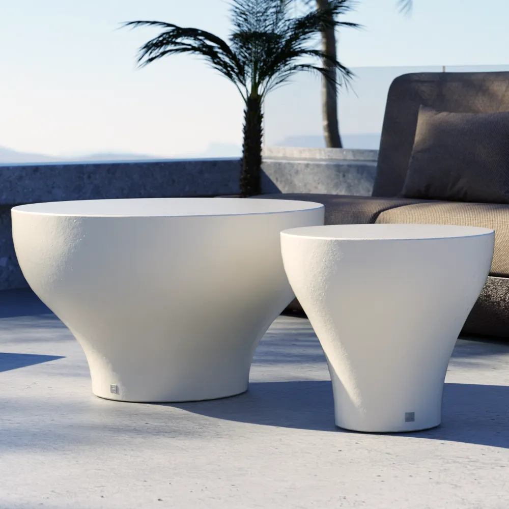 Detalhe de duas mesas de apoio brancas do conjunto Bloom para exterior, com volumes afunilados e superfícies lisas junto a zona lounge.