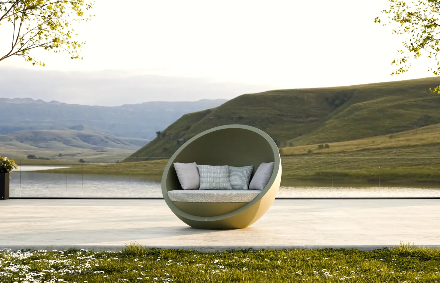 Bola outdoor sofa in green on a spacious terrace overlooking a lake and hills, showing its circular shape and cushioned seat.