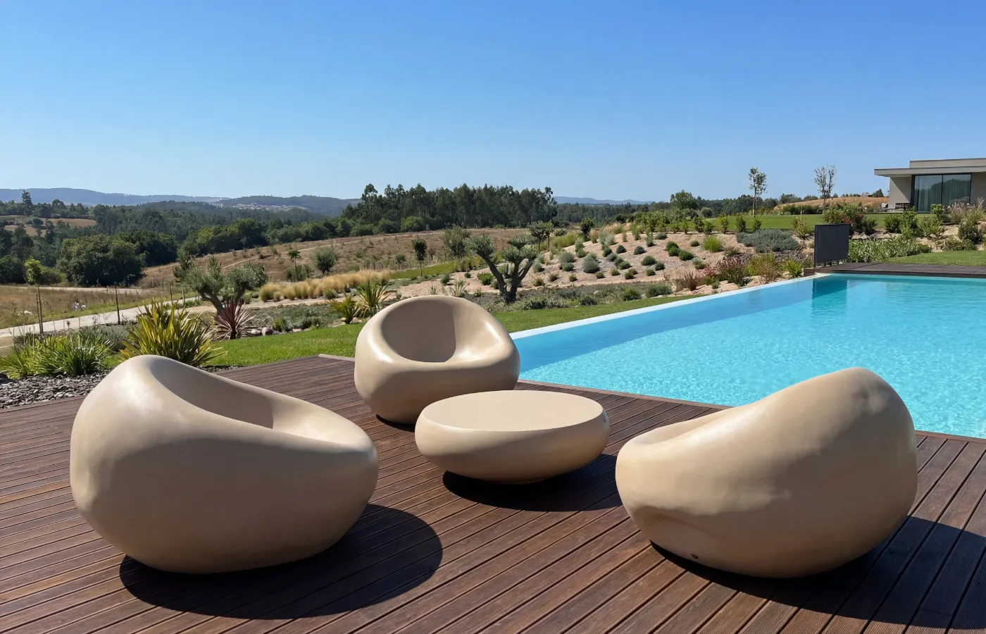 Sofás Cobble em bege e mesa centro Ariel dispostas num deck junto à piscina, com formas suaves e arredondadas.