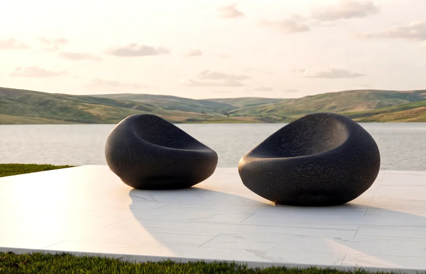 Dois sofás Cobble em textura vulcânica em terraço com vista para lago e colinas, destacando a forma orgânica arredondada.