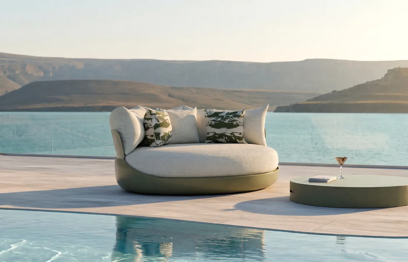 A green Harmony daybed with side table in an outdoor poolside setting, overlooking the sea and natural landscape.