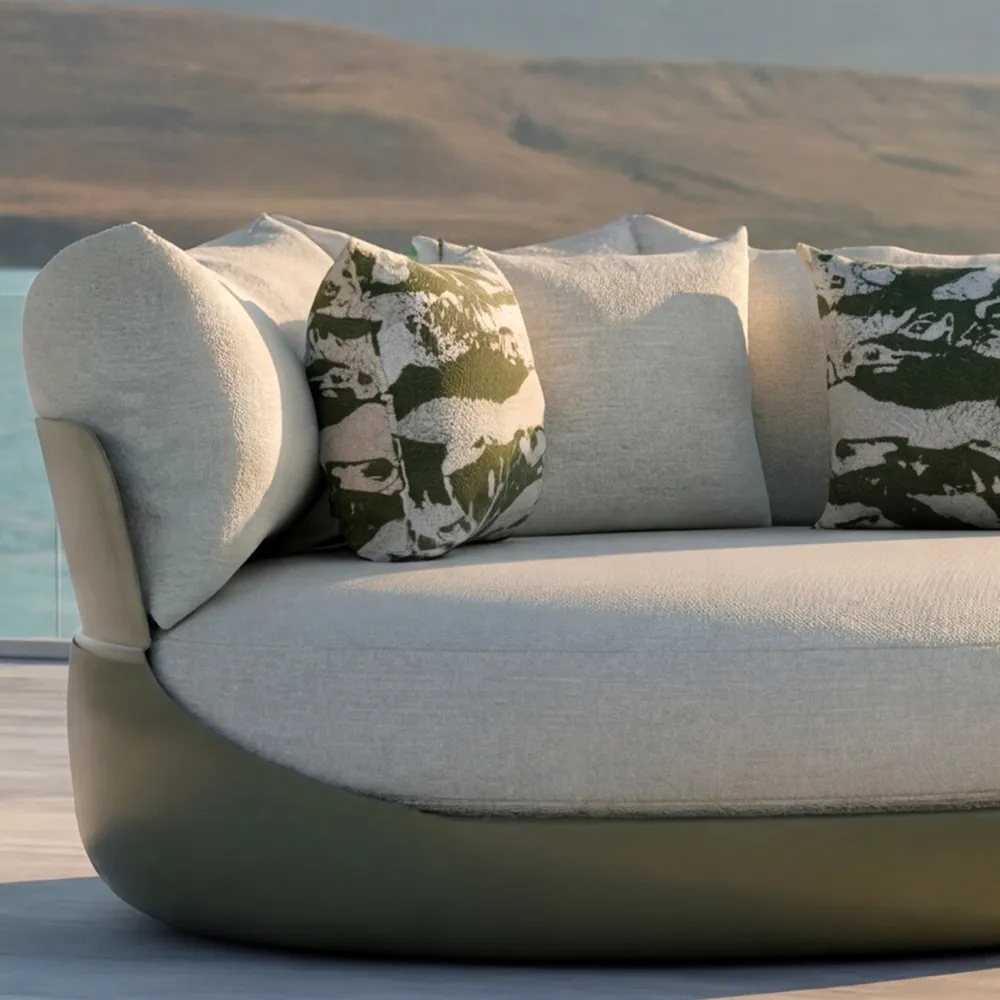 Close-up of the Harmony green daybed with cushions and textured upholstery in an outdoor seaside setting.
