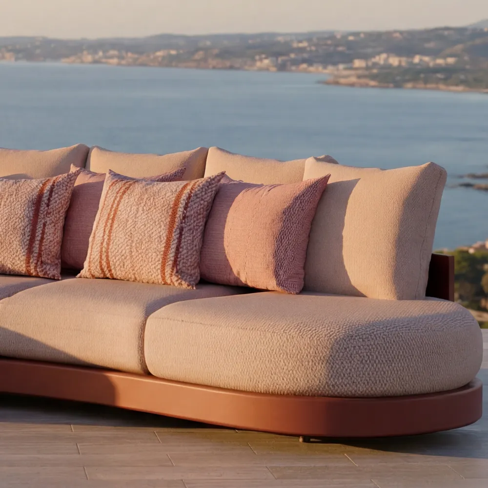Close-up of the terracota Harmony sofa with cushions and textured upholstery in an outdoor seaside setting.