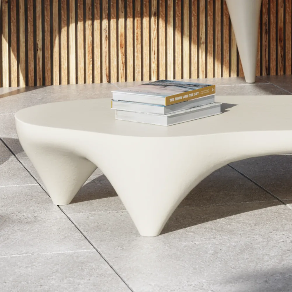 Detalhe da mesa de centro Ivory para exterior em branco, mostrando a transição entre o tampo orgânico e os apoios curvos da base.