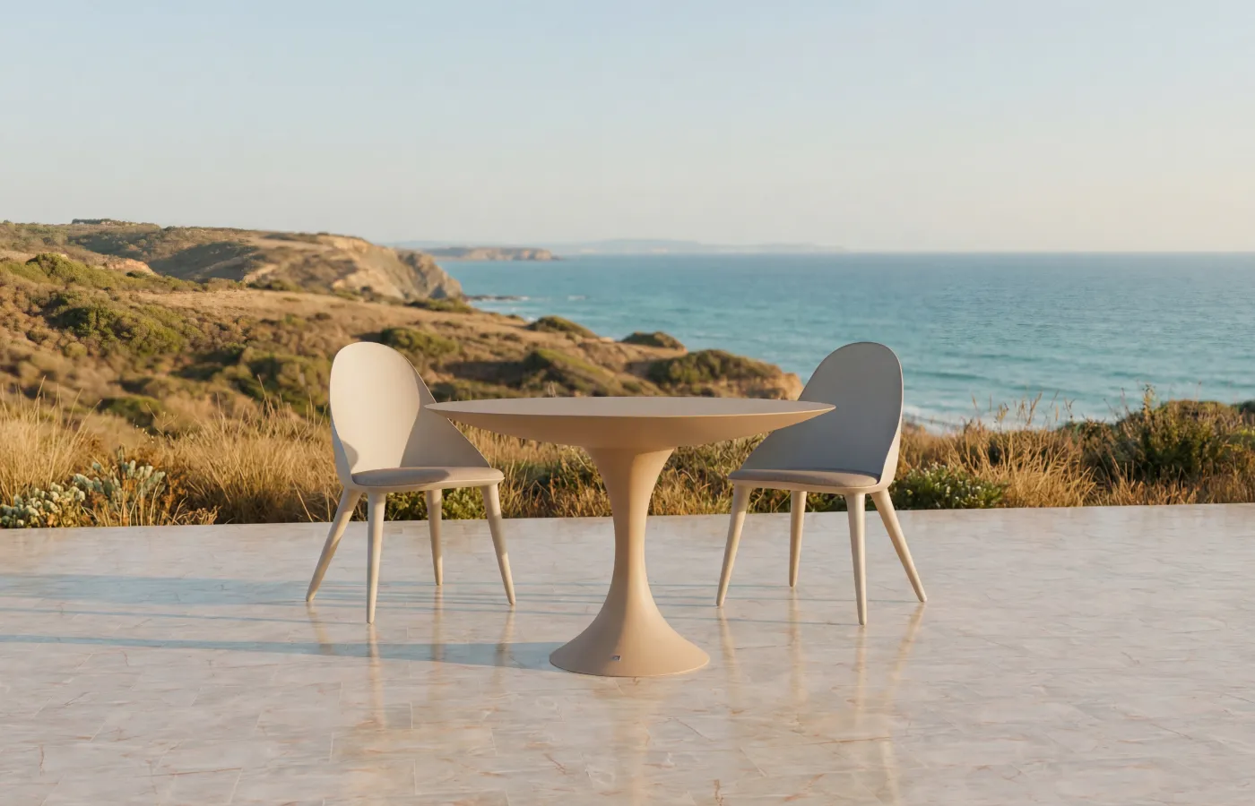 Mesa de jantar redonda Jade beige para exterior, entre duas cadeiras Mónaco, numa varanda com vista para o mar.