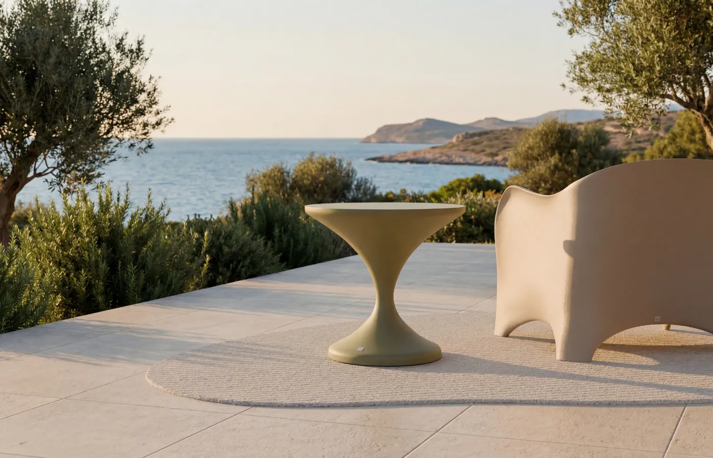 Lya outdoor side table in matte green, placed beside a Oceano armchair on a terrace overlooking the sea.