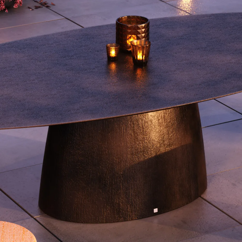 Detalhe da mesa de jantar Magna, com tampo oval e base central larga com textura côco.