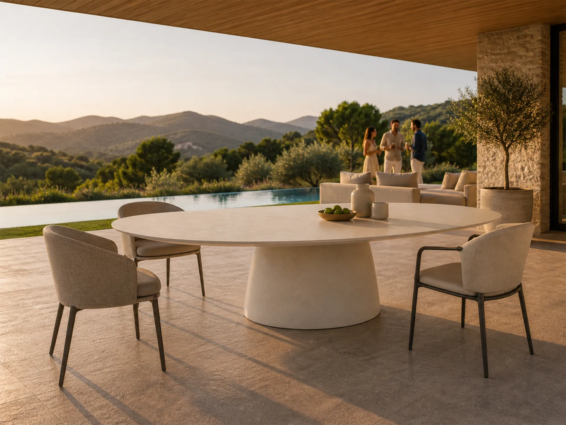 Terraço exterior junto à piscina com mesa de jantar Magna oval em branco com cadeiras estofadas e pessoas ao fundo junto a sofá.