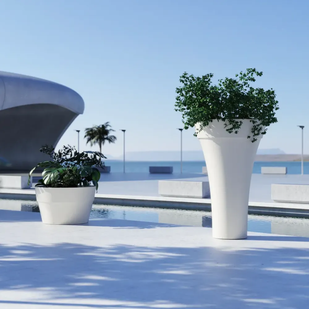 Close-up of a white Maximo planter with a tall tapered shape and green plant, placed beside a reflecting pool on an outdoor terrace.