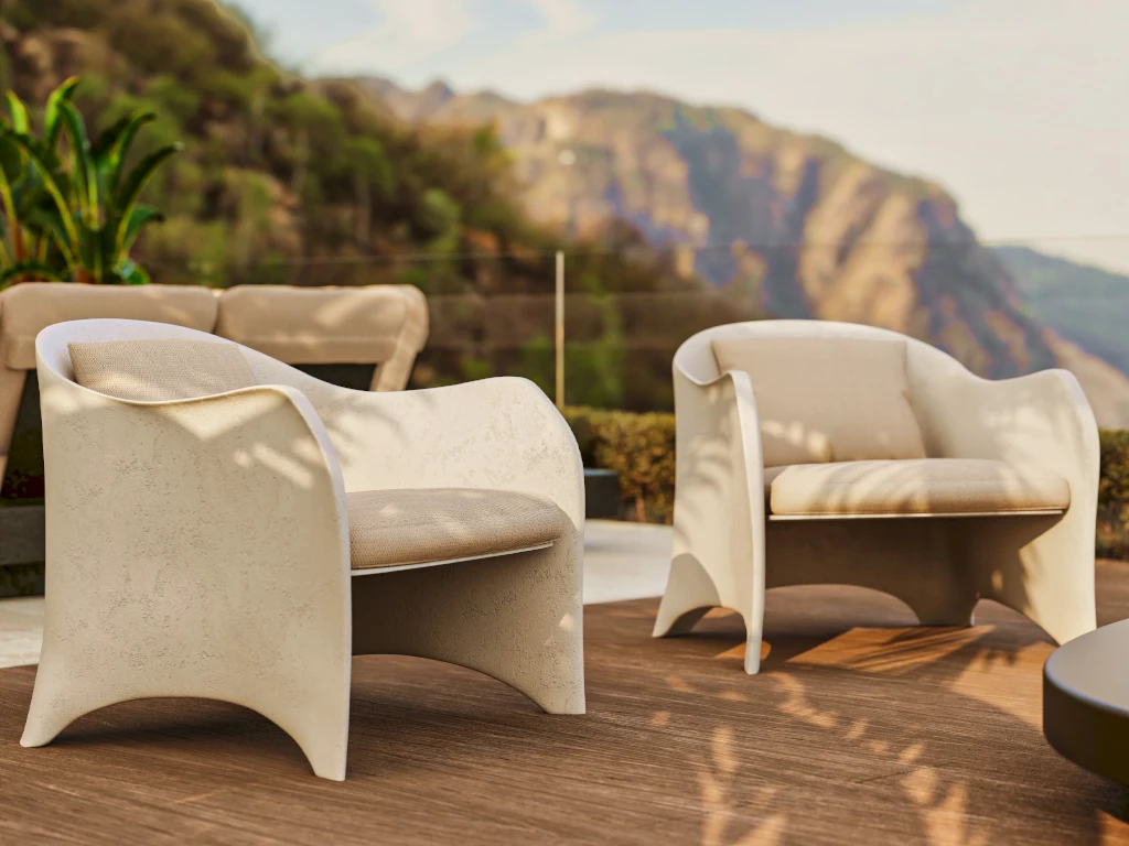 Two Oceano armchairs in white with volcanic texture on an outdoor terrace, with light cushions and an enveloping frame with soft lines.