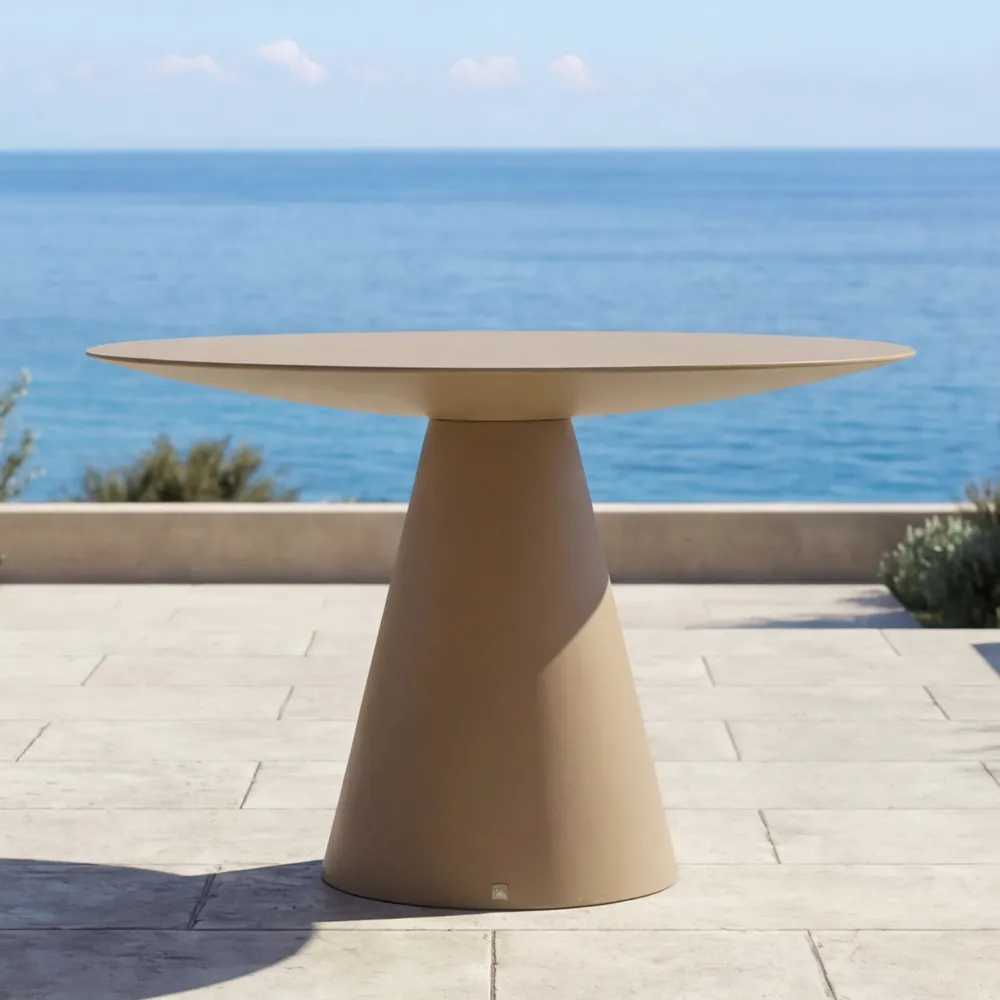 Detail of the Oceano dining table in chalk beige, highlighting the slim top and conical central base by the sea.