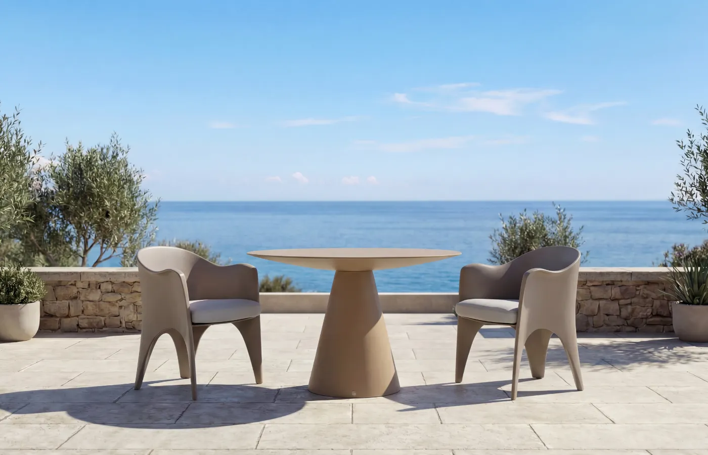 Oceano round outdoor dining table in chalk beige, set between two Oceano chairs on a sea-view terrace.