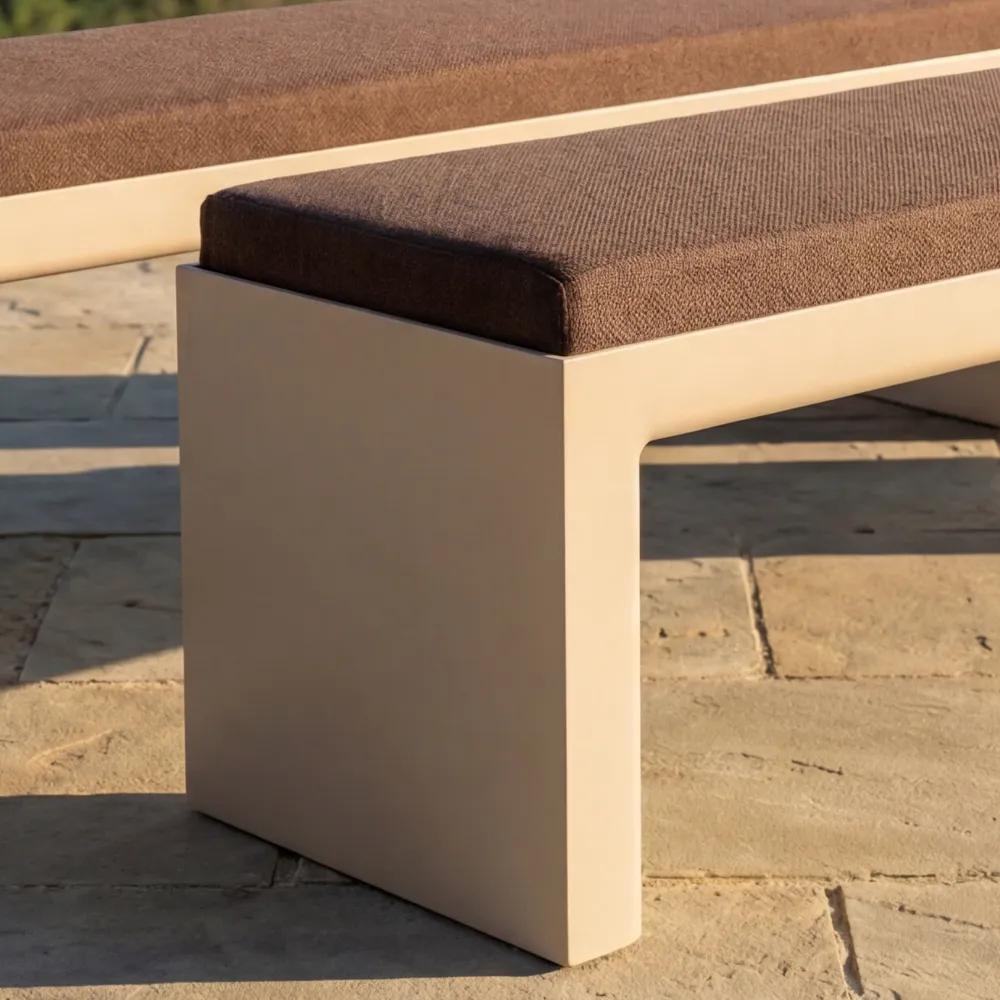 Detail of the Quadra bench in white showing the cushioned seat and the junction between the upholstered volume and linear frame.