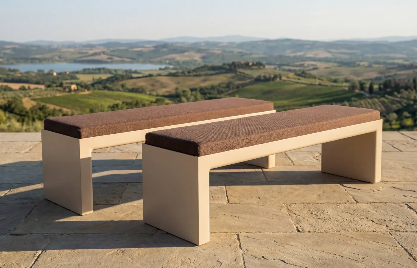 Two Quadra benches in white with cushioned seats on an outdoor terrace, highlighting the linear frame and low profile.
