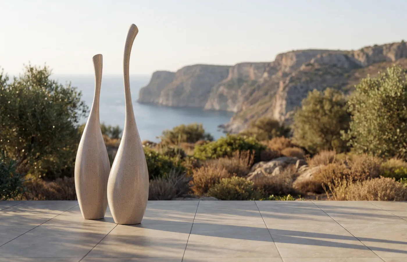 Solitary decorative pieces in sand finish on a terrace with coastal view, with tall, elongated organic shapes.