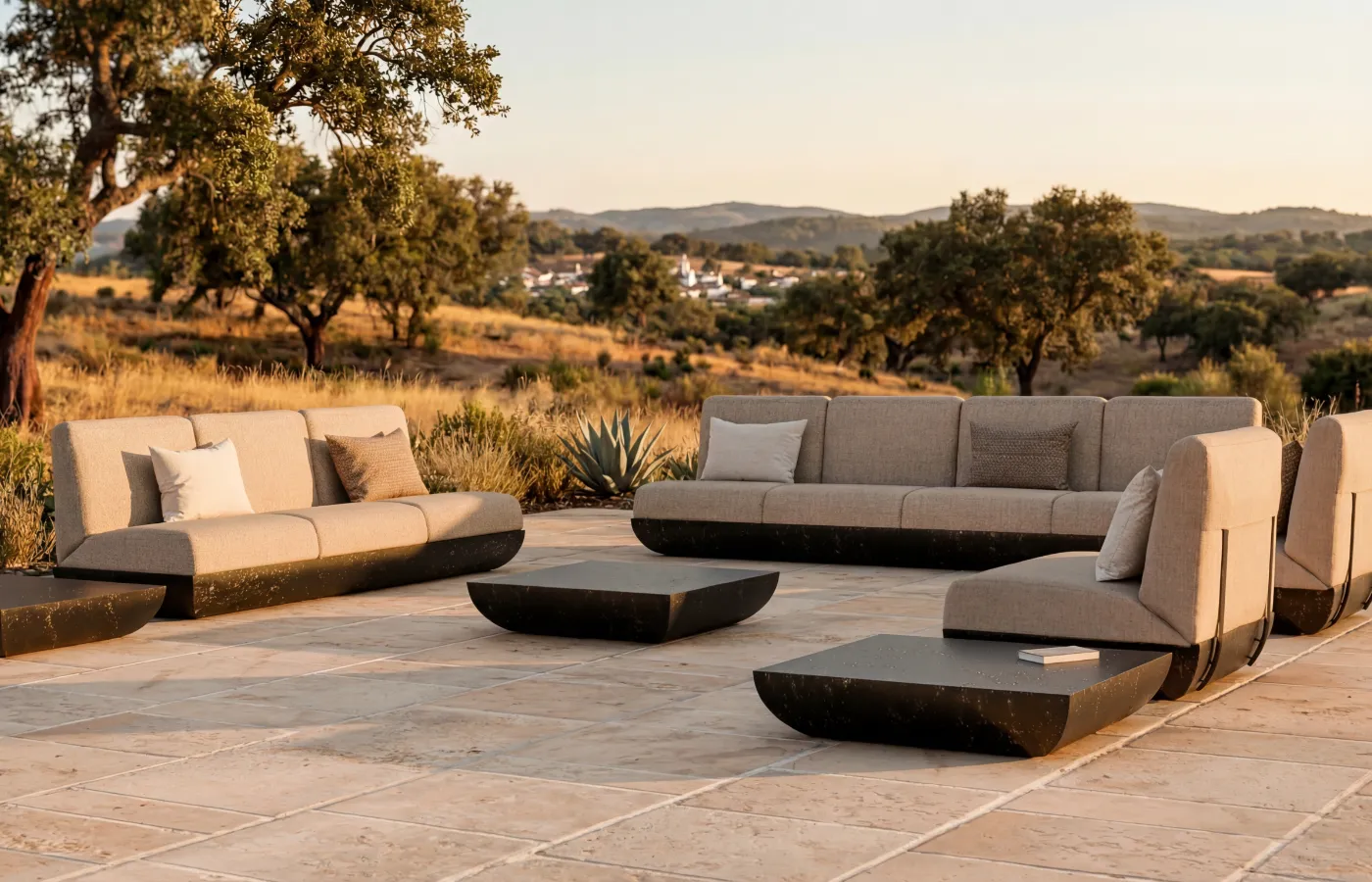 Sofás Victoria em textura ardósia, em composição exterior com mesas de centro Victoria, módulos estofados e base arredondada em terraço aberto.