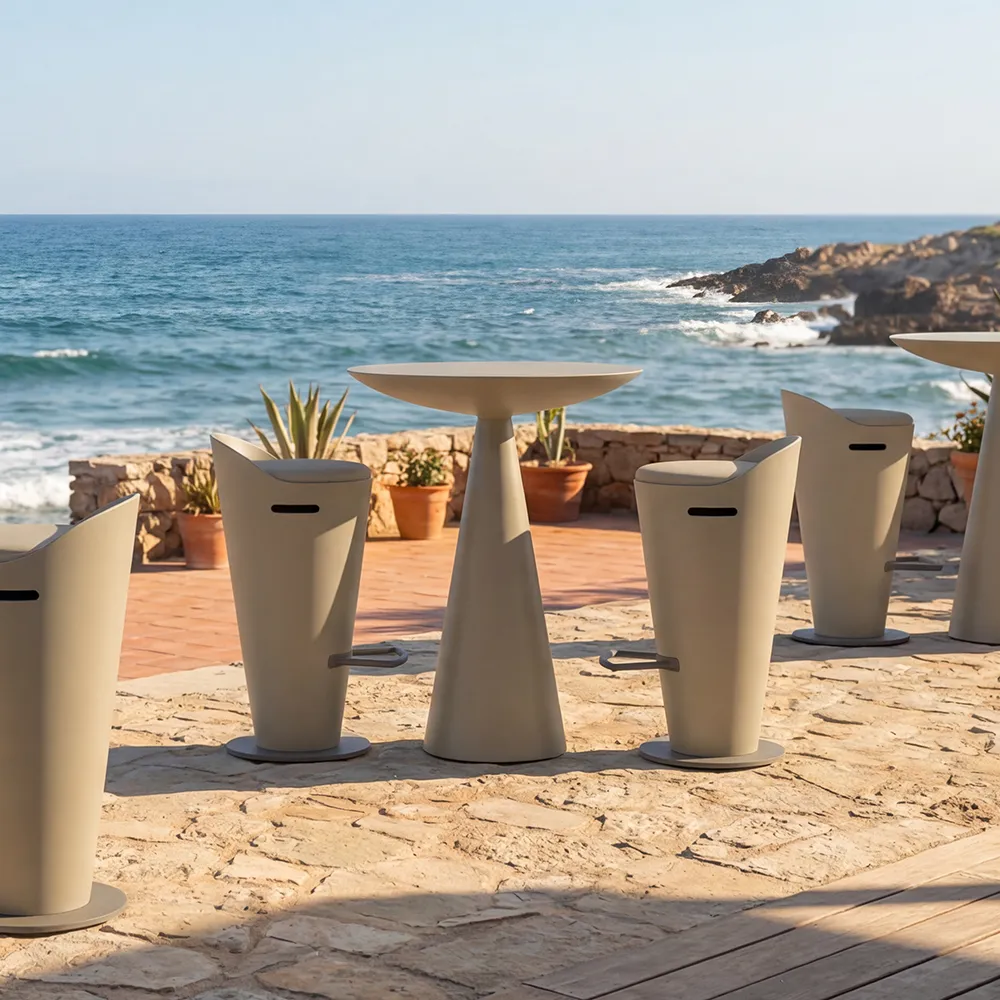 Outdoor terrace by the sea featuring a set of beige Oceano bar tables with Selene stools